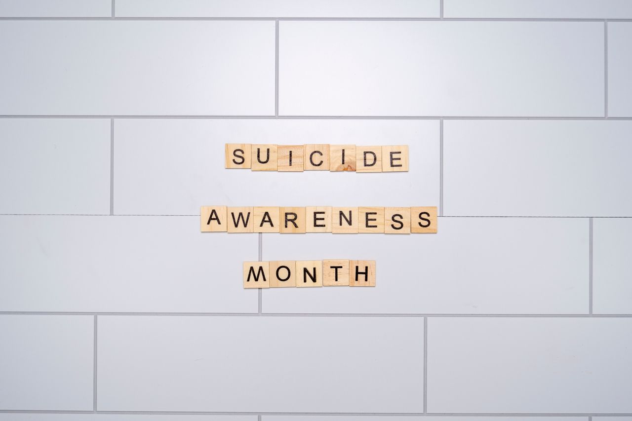 About us Suicide Awareness Month spelled with Scrabble tiles on a light background symbolizes mental health awareness.