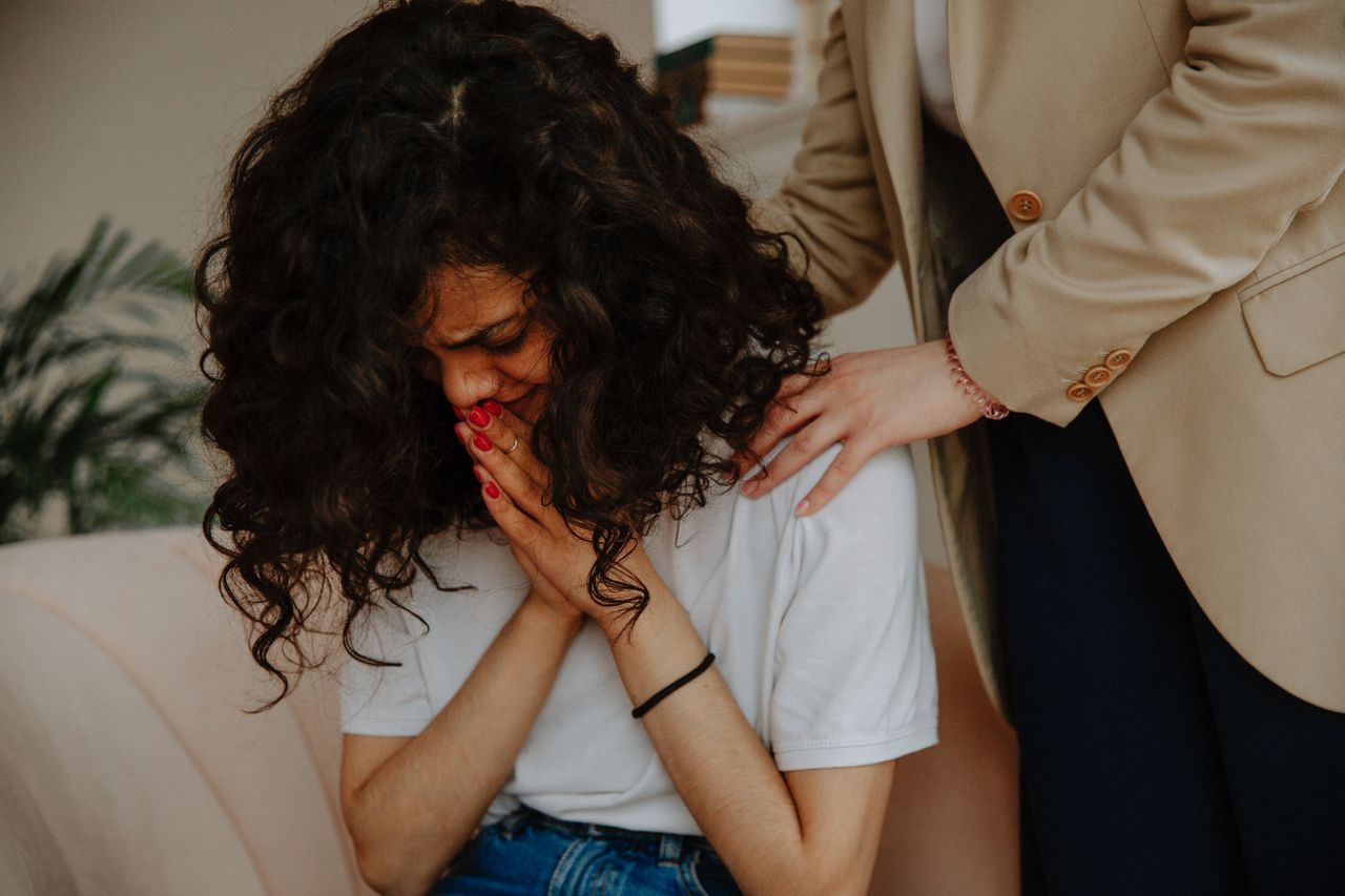 About us A young woman receiving comforting and emotional support during a therapy session.